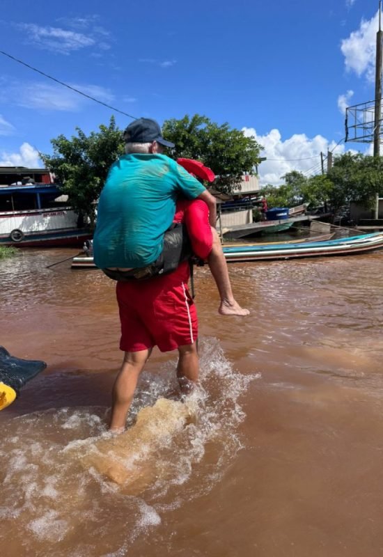 Bombeiro carrega idoso nas costas durante resgate em área alagada no Rio Juruá